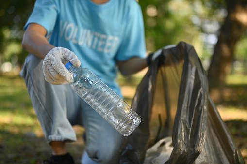 Young woman volunteer collecting plastic bottle in the park. Environmental protection concept.