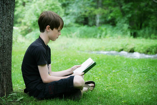 istock Happy Child Reading A Book Outside in Nature 182410765