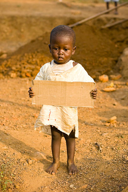 istock African boy holding a blank cardboard sign 182411274