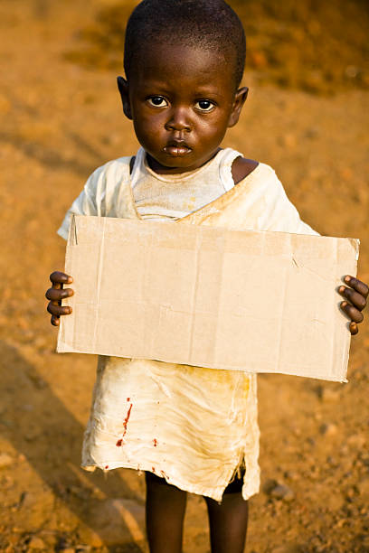istock African boy holding a blank cardboard sign 182411278