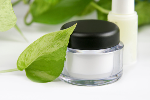 natural face care cream in a transparent container and green leaf aside