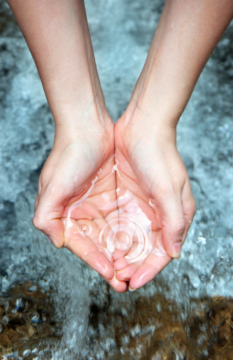 woman's hands over a water cascade