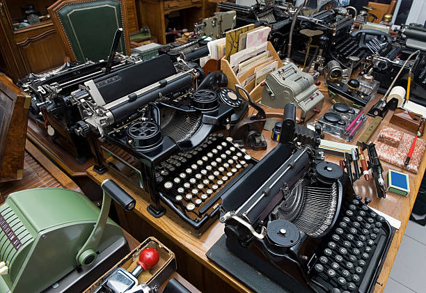 Old typewriter with old phone on the table with lamp  on the background