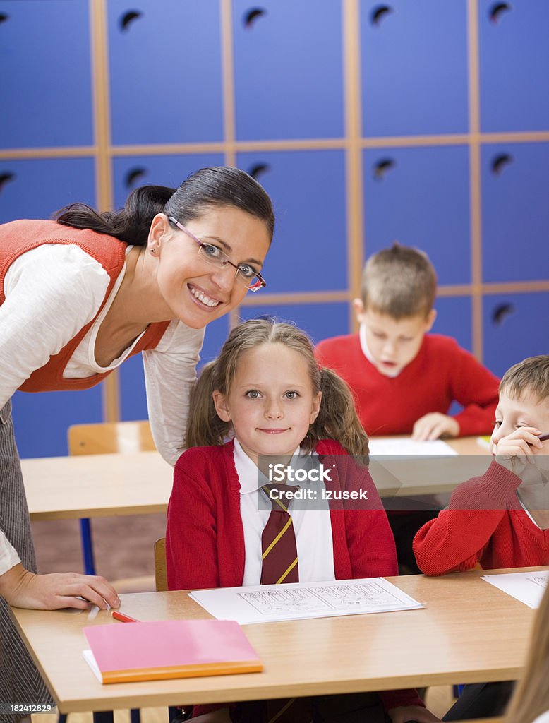Elementary School Children Teacher Helping Happy teacher helping a school girl in a classroom. They are both looking at camera smiling. 6-7 Years Stock Photo