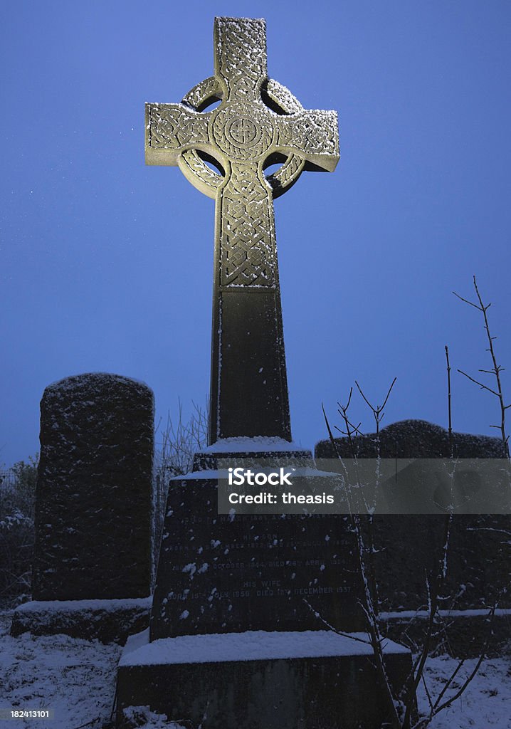 Celtic Cross In An Urban Graveyard A celtic cross gravestone in a dilapidated Victorian Glasgow cemetery at night. Slight dusting of snow and light snow falling. Carving - Craft Product Stock Photo