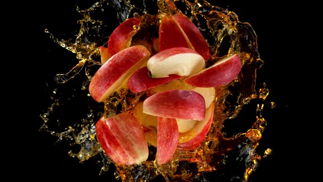 Super Slow Motion of Rotating Red Apple Slices Into Juice on Black Background.