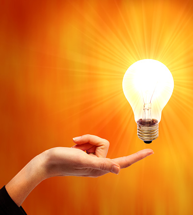 Idea symbol. light bulb on hand as a symbol of an idea. Orange background.