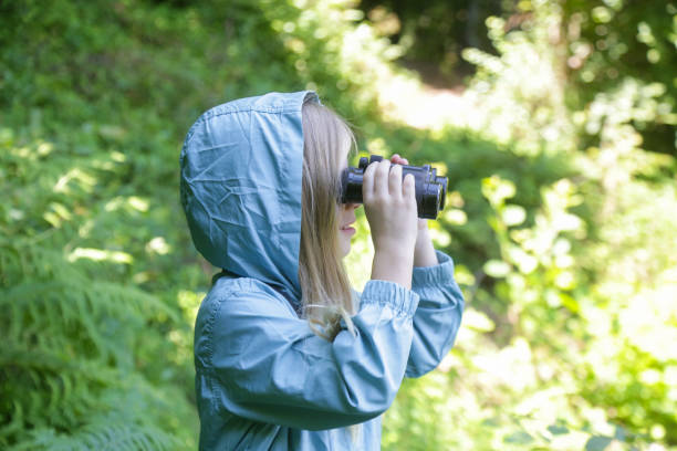 istock Cute little girl exploring nature looking through binoculars. Child playing outdoors. Kids travel, adventure and bird watching concept. 1824150947