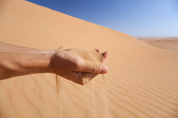 istock hand can«t stop sand from running through fingers - conceptual 182415239