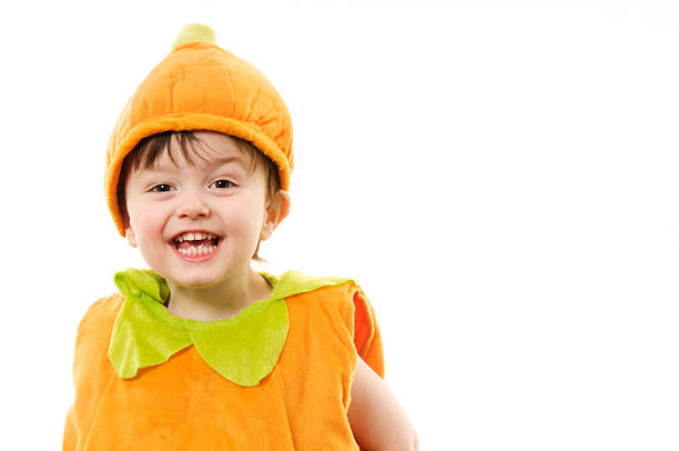 Three year old boy posing wearing pumpkin costume
