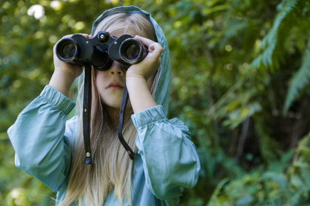 istock Cute little girl exploring nature looking through binoculars. Child playing outdoors. Kids travel, adventure and bird watching concept. 1824154401