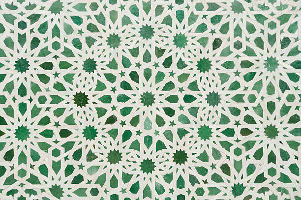 Arabic Islamic Zellige mosaic wall detail background stock photo "Detail of wall in Fez, Morocco showing colors of Islam and geometric shapes. Use for background. The same designs are used for floors too. Green in the color of Islam.Zellige, Zillij or Zellij (Arabic: AaAa Aa) is terra cotta tilework covered with enamel in the form of chips set into plaster." moroccan culture photos stock pictures, royalty-free photos & images