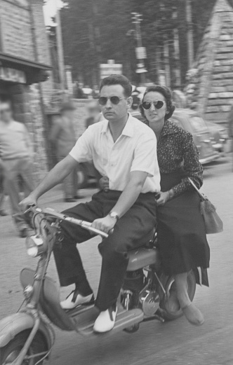Young couple on vintage motor scooter in a street. 1952.