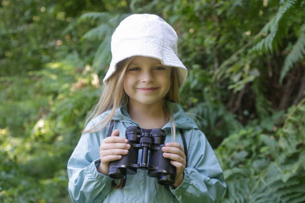 istock Cute little girl exploring nature looking through binoculars. Child playing outdoors. Kids travel, adventure and bird watching concept. 1824163206