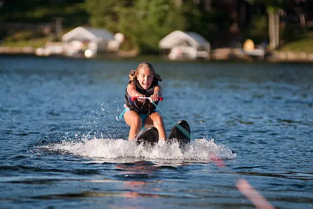 Girl beginning to waterski and getting up from the water