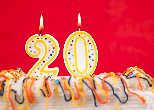 istock Decorated birthday cake with number 20 buring candles.  Red background. 182417090