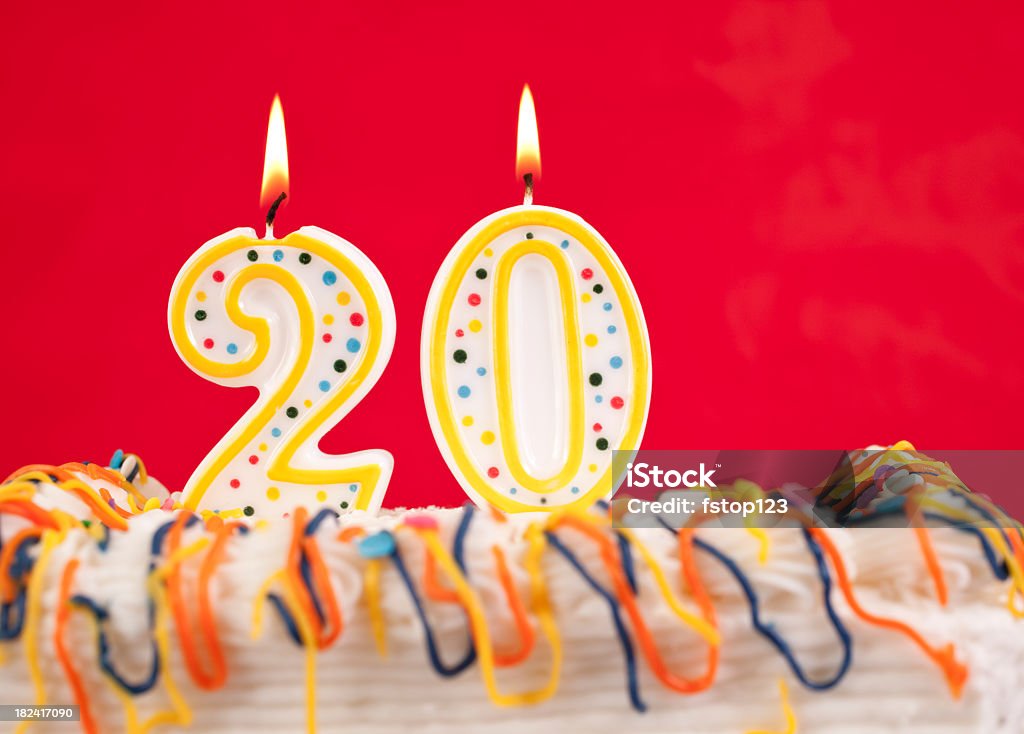 Decorated birthday cake with number 20 buring candles.  Red background. Decorated cake  with number 20 candles.  Red background Anniversary Stock Photo