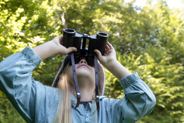 istock Cute little girl exploring nature looking through binoculars. Child playing outdoors. Kids travel, adventure and bird watching concept. 1824170901