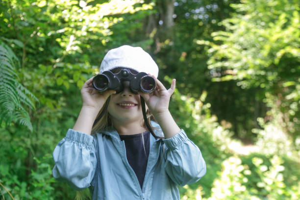 istock Cute little girl exploring nature looking through binoculars. Child playing outdoors. Kids travel, adventure and bird watching concept. 1824173635