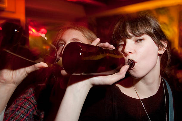 2 つの魅力的な若い女性のビールを飲みながら、バーで - two party system ストックフォトと画像