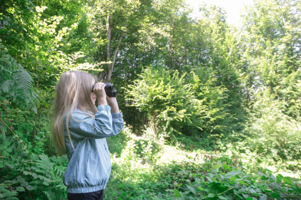 istock Cute little girl exploring nature looking through binoculars. Child playing outdoors. Kids travel, adventure and bird watching concept. 1824180086