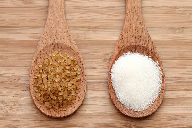 istock White and brown sugar in a wooden spoons 182418125