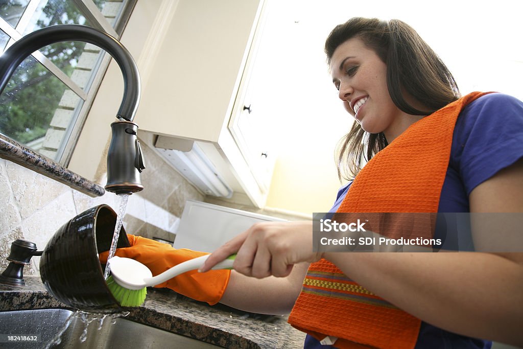 Junge Frau Reinigung Küche mit Schrubber in der Spüle - Lizenzfrei Orange - Farbe Stock-Foto