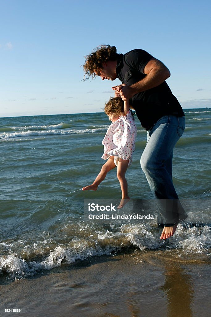 Father and Daughter at the Beach A dad plays in the waves with his baby girl. Some copy space in sky. 12-17 Months Stock Photo