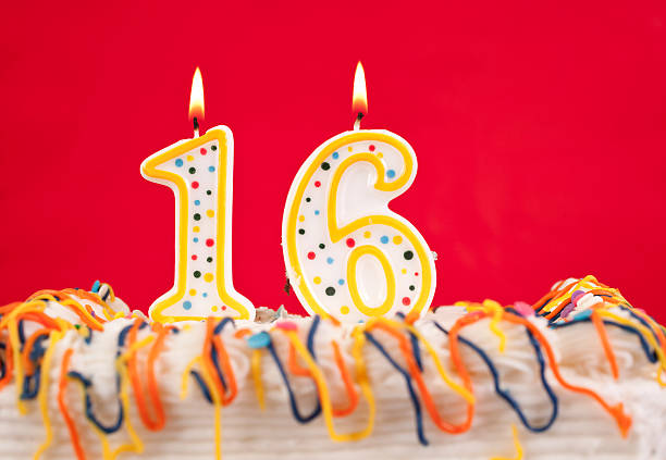 istock Decorated birthday cake with number 16 buring candles.  Red background 182419321