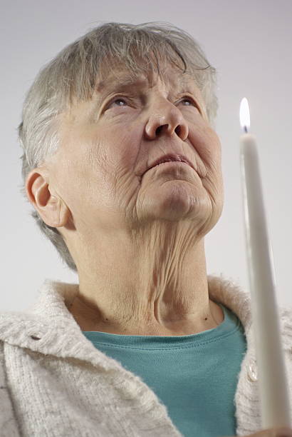istock Senior Woman Holds Candle While Praying 182419543