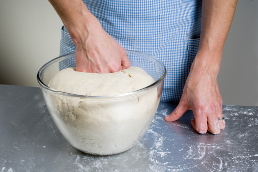 A ball of freshly made dough rising in a glass bowl ready to be kneaded.