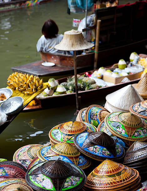 Ratchaburi Province. Thailand - February 19, 2011: A fruit vendor sells her product at the well-known tourist destination of Damnoen Saduk floating market in Ratchaburi Province. This famous market becomes a hive of colourful activity in the mornings.