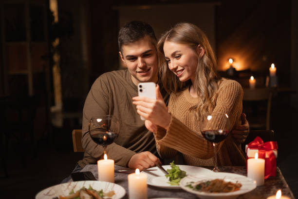 istock Browsing internet during romantic date dinner at home. Happy couple looking photos on smartphone during celebrating Valentines Day 1824207434