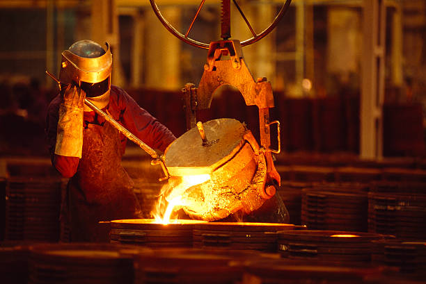 Man Working In a Foundry Man Pouring Glowing Metal Alloy foundry photos stock pictures, royalty-free photos & images