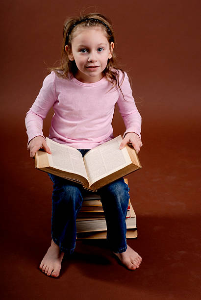 istock Little Girl Reading A Large Book Series 182420991
