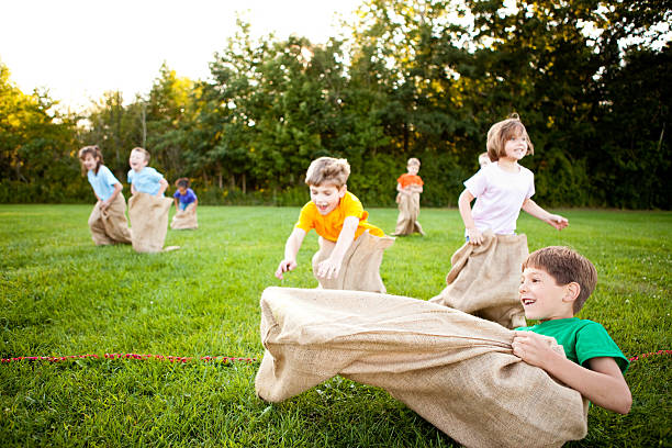 felizes crianças tendo uma divertida corrida de saco de fora de batata - child playing sack race sports race - fotografias e filmes do acervo