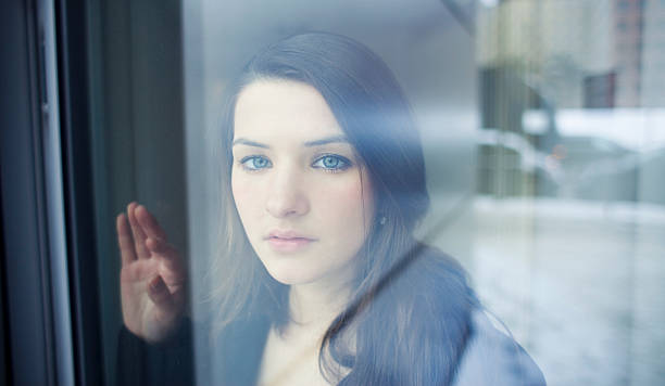 istock Young Woman Looking through Window with Longing 182421380