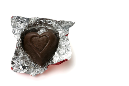 An unwrapped chocolate candy heart isolated on white; clipping path available for the chocolate and wrapper. Copy space on right.