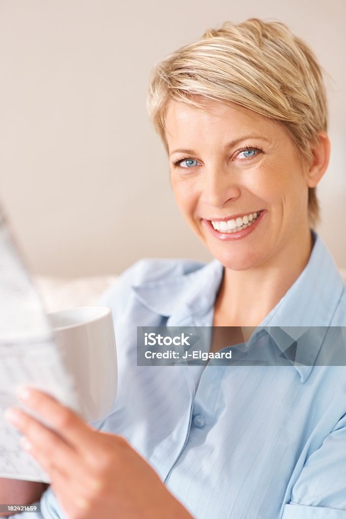 Mujer feliz leyendo un periódico mientras disfruta de un café - Foto de stock de 30-39 años libre de derechos