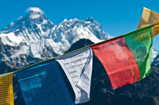 "Brightly colored Buddhist prayer flags flying in a deep blue high altitude sky over the iconic pyramid peak of Mt. Everest and the snow capped summits of Nuptse, Lhotse and the Western Cwm high in the remote Himalaya of Nepal. ProPhoto RGB profile for maximum color fidelity and gamut."