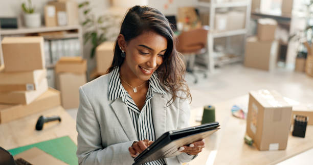istock Small business, woman and boxes with tablet, e commerce and startup inventory management for online shop, order or courier. Entrepreneur or young seller on digital technology for logistics or package 1824226146