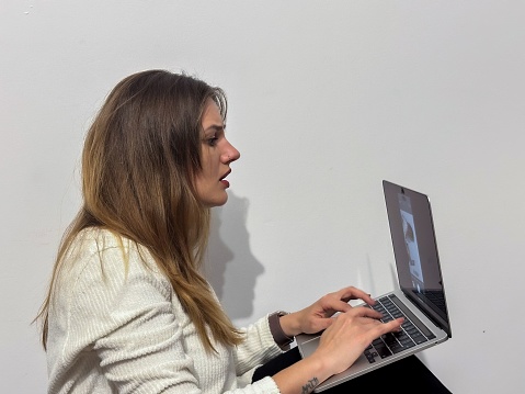 A portrait of a young Caucasian woman typing on a laptop.