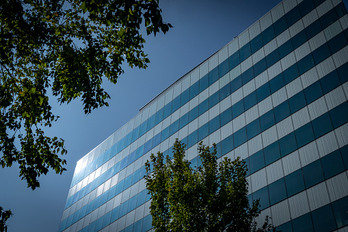 Modern glass office building with blue sky background. Bank financial office building wall. Real estate.