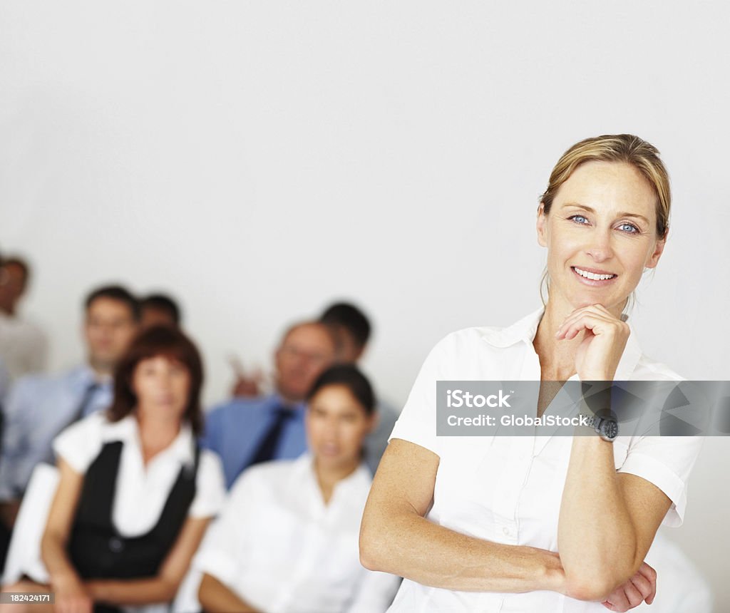 Donna matura affari con i suoi colleghi in background - Foto stock royalty-free di 20-24 anni