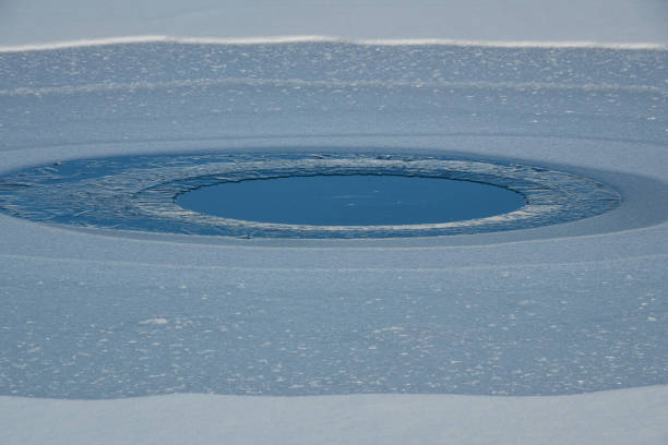 Icy circular mountain lake surrounded by snow