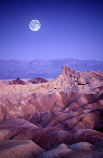 The moon setting over zabriskie point at death valley.
