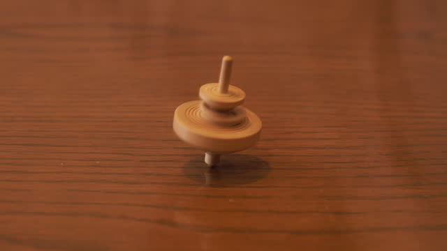 View of spinning wooden top on wooden table