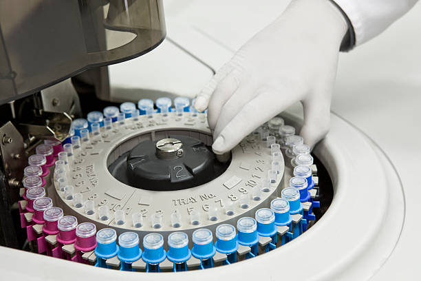 worker putting blood samples into blood analyzer machine - santrifüj stok fotoğraflar ve resimler