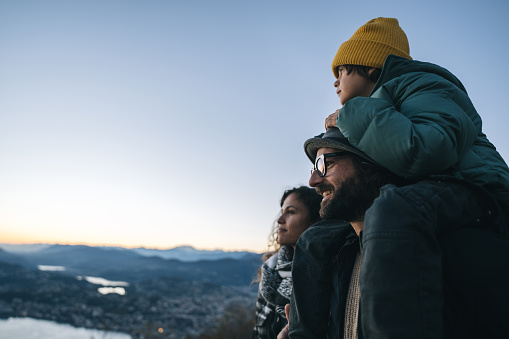Portrait of family on mountain top above lake at sunset