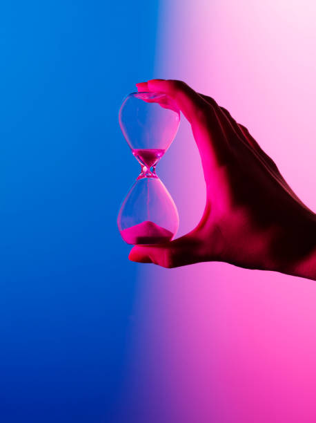 divisée en couleur sablier - sand clock human hand hourglass photos et images de collection